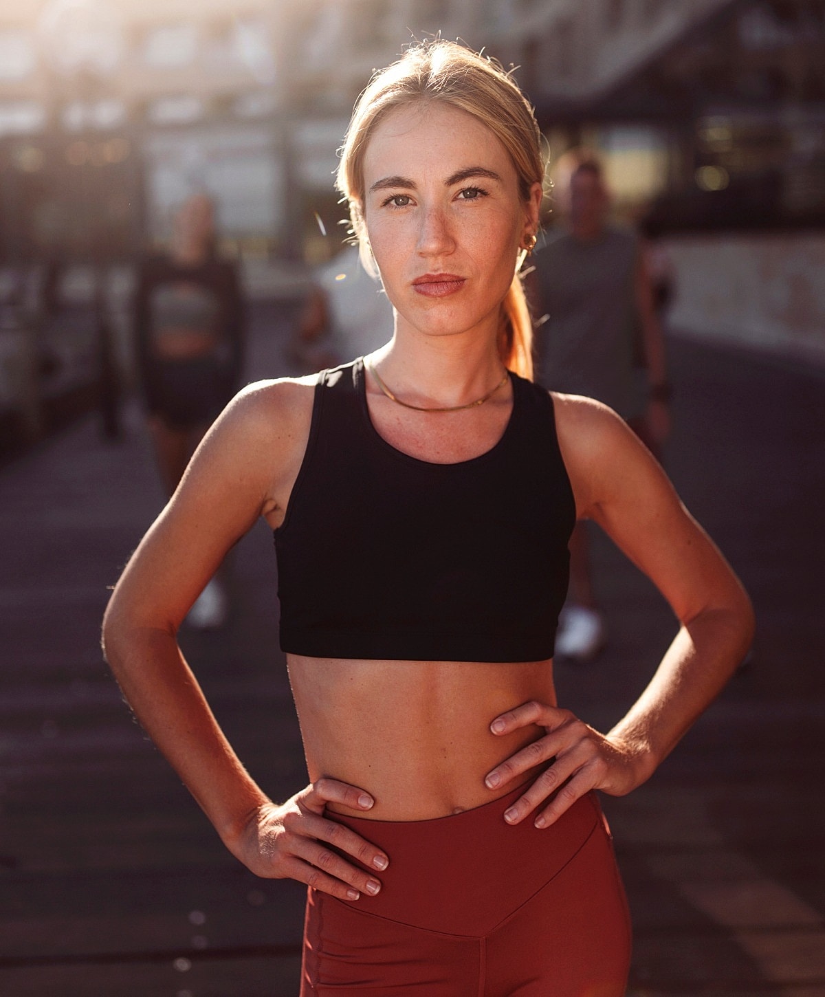 Woman in activewear posing outdoors at sunset.