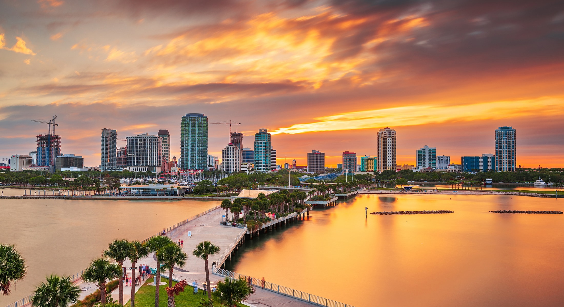 Downtown skyline at sunset with calm water.