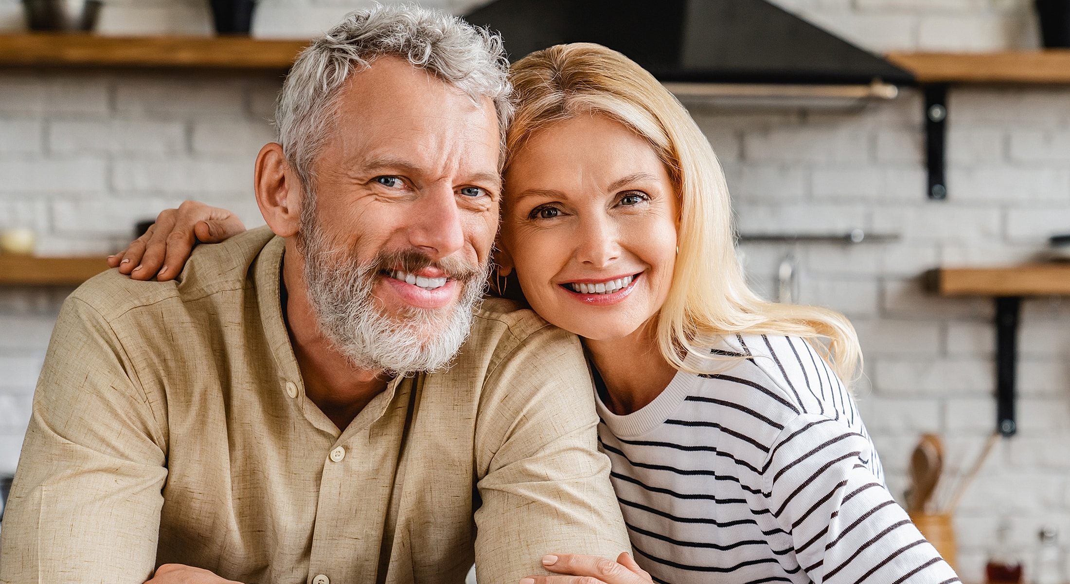 Happy couple smiling in a kitchen setting.